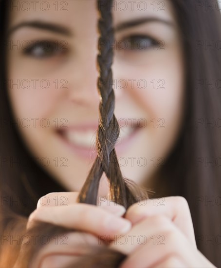 Young woman braiding her hair. Photo : Jamie Grill