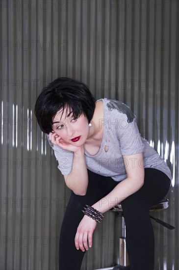 Bored woman slouching on a stool. Photo. Daniel Grill