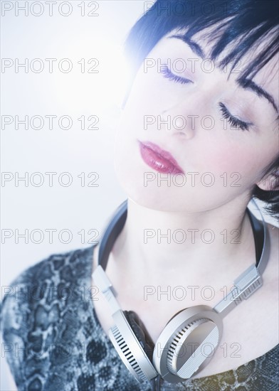 Relaxed woman with headphones around her neck. Photo : Daniel Grill