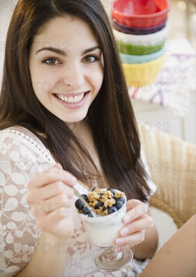 Brunette woman eating granola and yogurt. Photo : Jamie Grill