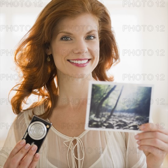 Woman holding camera and photograph. Photo : Jamie Grill