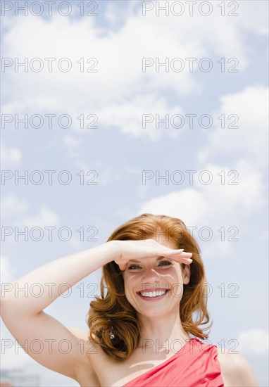 Beautiful woman shielding her eyes from the sun. Photo. Jamie Grill