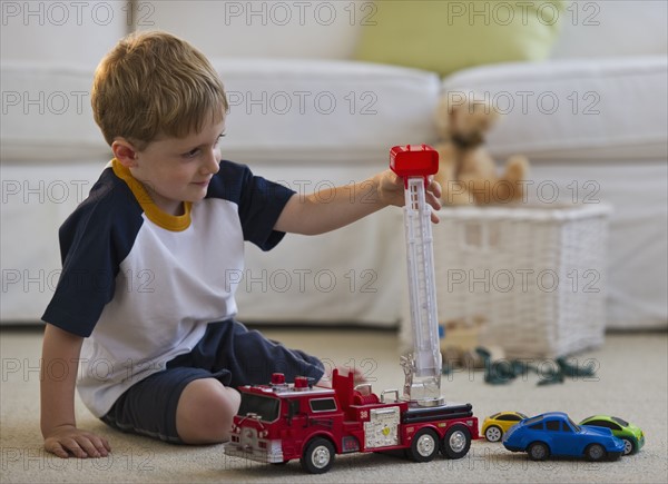 Young boy playing with toy fire truck. Photo : Daniel Grill