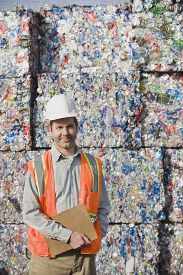 Worker standing in front of crushed aluminum cans. Photo. Erik Isakson