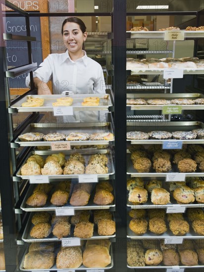 Baker standing behind trays of baked goods.