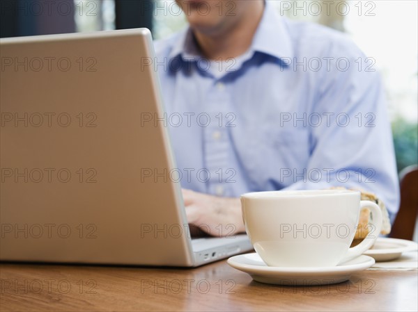 Man working on laptop in restaurant.