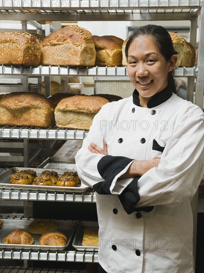 Chef standing beside trays of freshly baked goods.