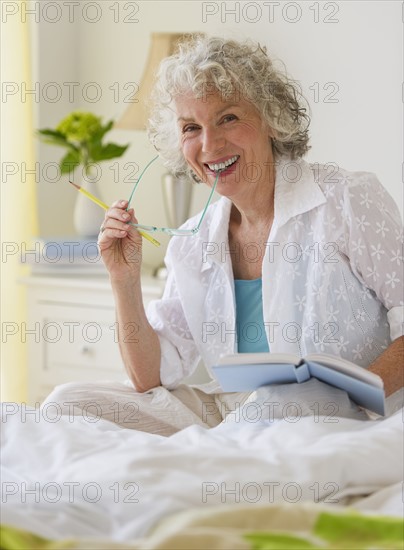 Woman reading a book in bedroom. Photo : Daniel Grill