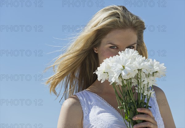 Woman holding flowers in front of her face.