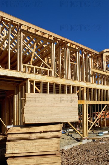 Stacks of plywood in front of house frame. Photo : fotog