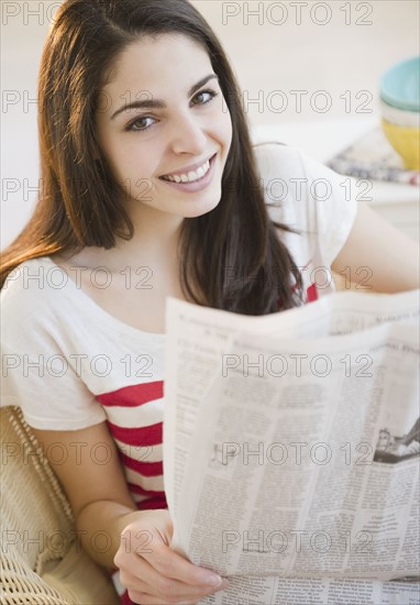 Brunette woman reading the newspaper. Photo : Jamie Grill