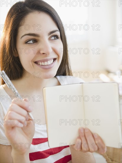 Brunette woman holding an empty notebook. Photo : Jamie Grill