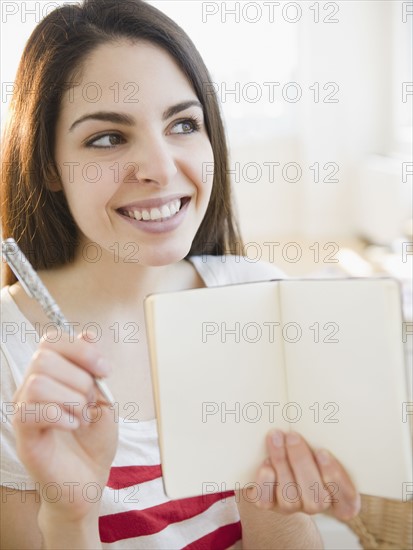 Brunette woman holding an empty notebook. Photo. Jamie Grill