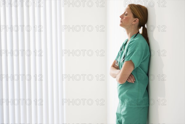 Tired doctor leaning against wall.