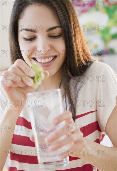 Woman squeezing lime into water. Photo : Jamie Grill