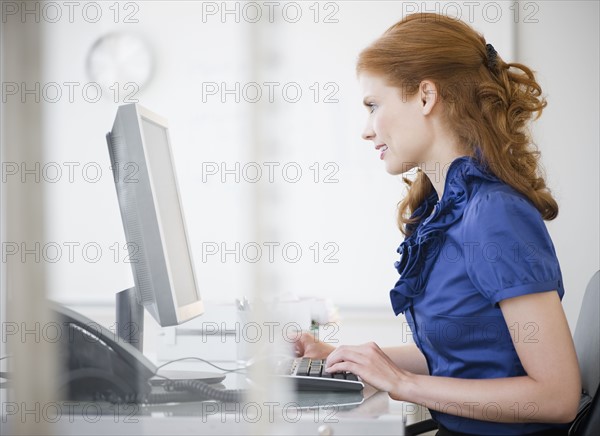 Businesswoman working at her desk. Photo : Jamie Grill