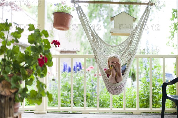 Young girl reading in hammock. Photo : Tim Pannell
