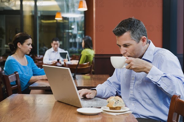 Man working on laptop in restaurant.