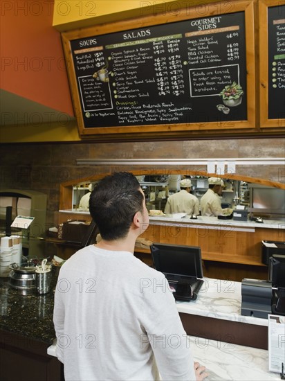 Customer reading chalkboard menu. Photo. Erik Isakson