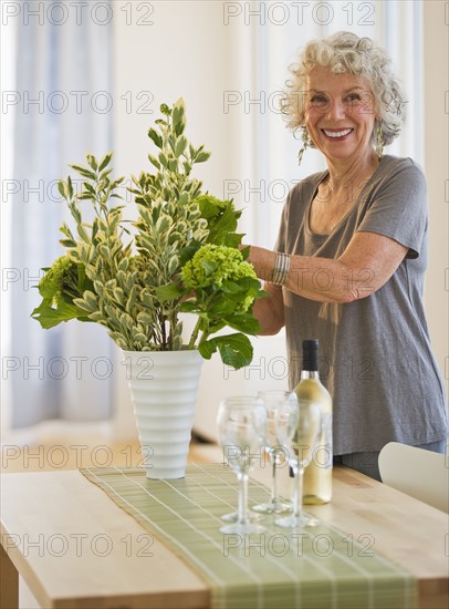 Woman arranging flowers in a vase. Photo. Daniel Grill