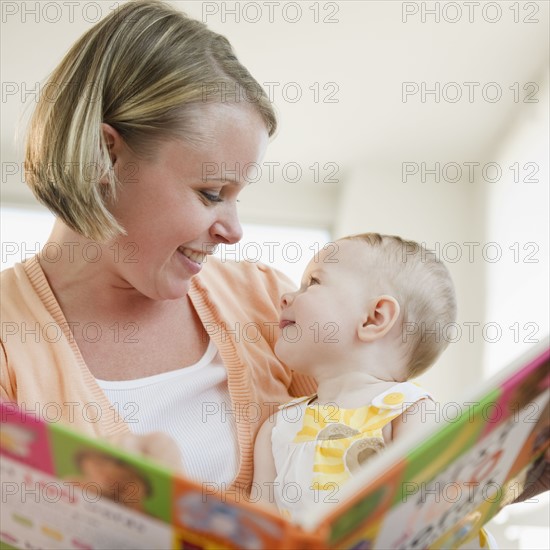 Mother reading book to her baby daughter. Photo. Jamie Grill