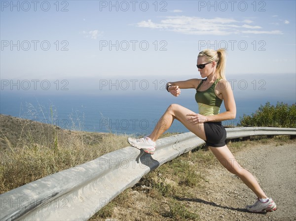 Runner stretching on the side of the road.