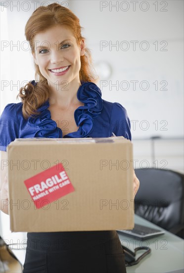Businesswoman holding a package. Photo : Jamie Grill
