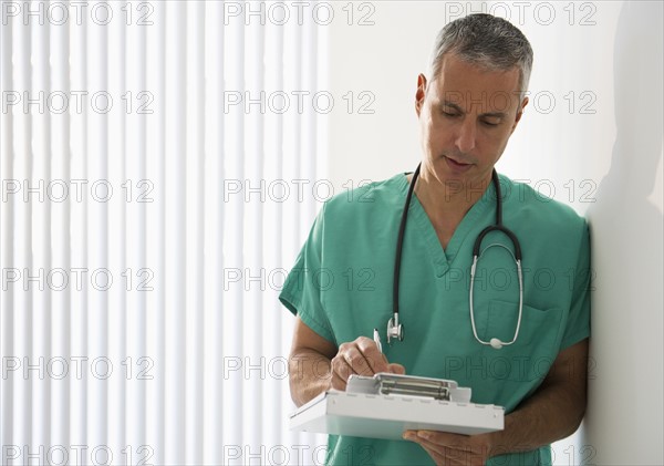 Healthcare worker writing on medical chart.