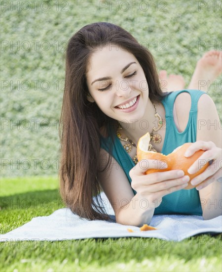 Young woman peeling an orange. Photo : Jamie Grill