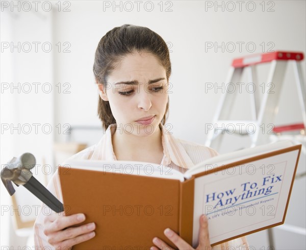 Confused woman reading do it yourself book. Photo. Jamie Grill