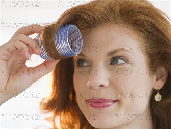 Woman putting curler in her hair. Photo : Jamie Grill