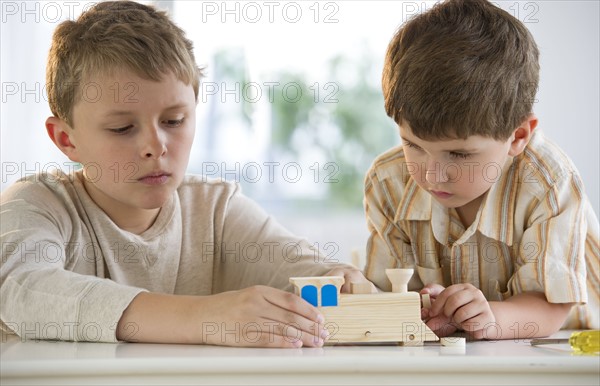 Two young boys building a wooden train.