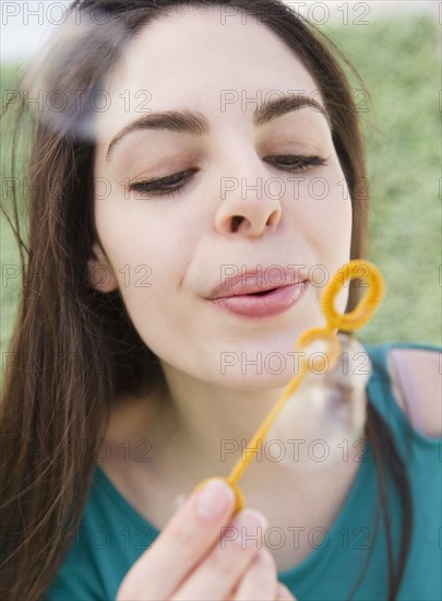 Young woman blowing bubbles. Photo : Jamie Grill