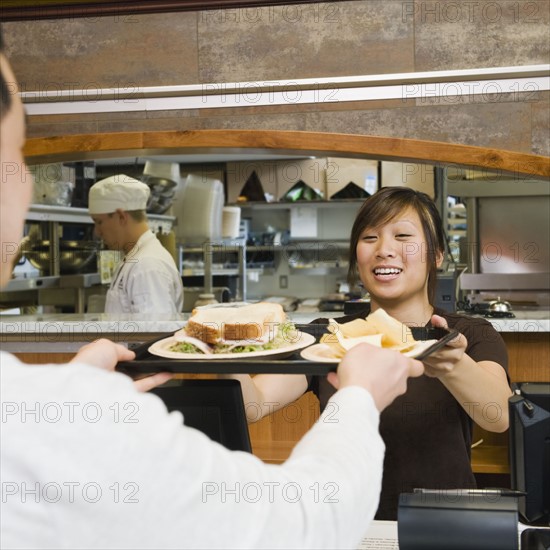 Customer receiving tray of food in bakery.