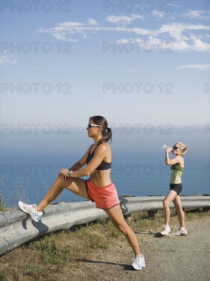 Runner stretching on the side of the road.