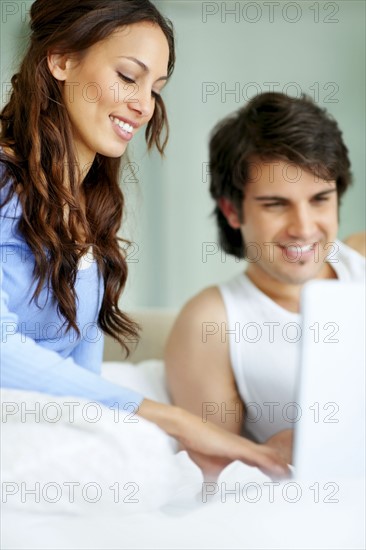 Couple looking at laptop together. Photo. momentimages