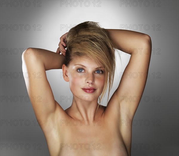 Seductive blond woman with her hands behind her head. Photo. momentimages