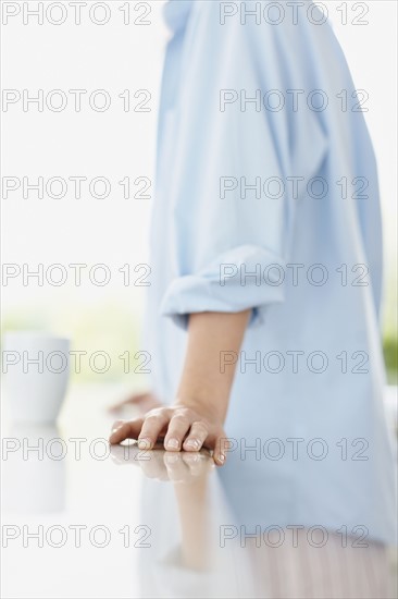 Woman leaning on kitchen counter. Photo : momentimages