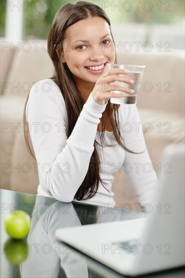 Woman drinking water while browsing the internet. Photo : momentimages