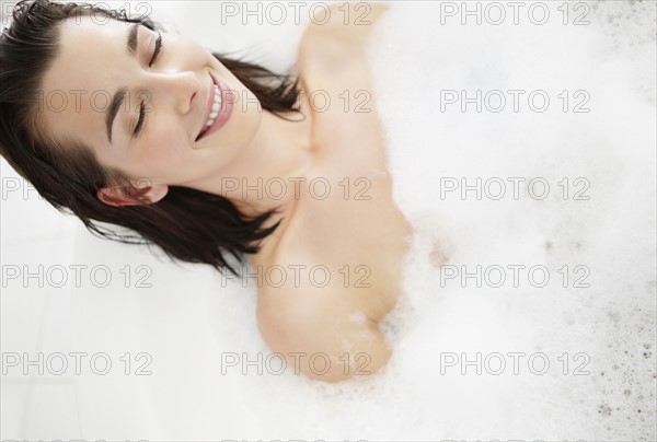 Contented woman in bubble bath. Photo. momentimages