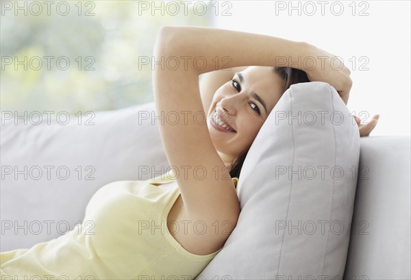 Cheerful brunette woman relaxing on couch. Photo : momentimages