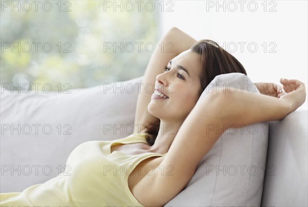 Cheerful brunette woman relaxing on couch. Photo. momentimages