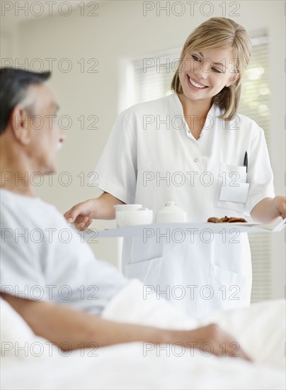 Nurse giving tray of food to patient. Photo : momentimages