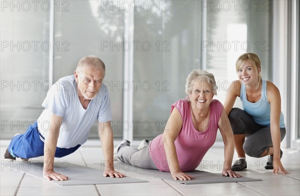 Senior couple exercising with a fitness instructor. Photo : momentimages
