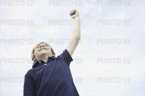 Young boy with his arm raised. Photo : momentimages