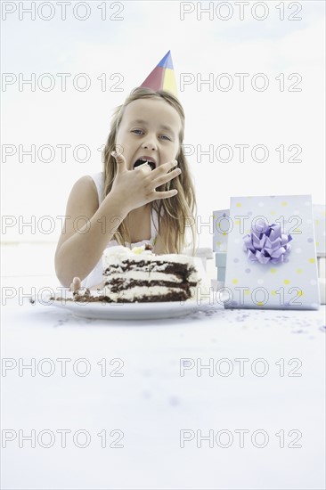 Young girl eating birthday cake. Photo. momentimages