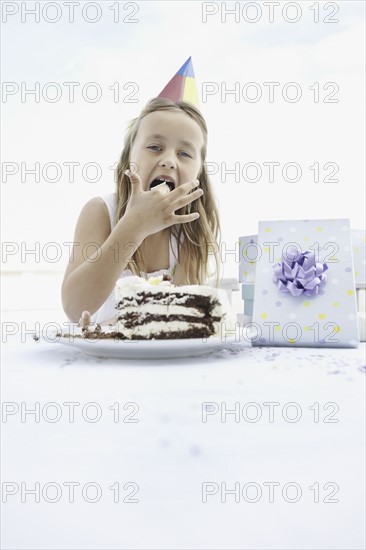 Young girl eating birthday cake. Photo : momentimages