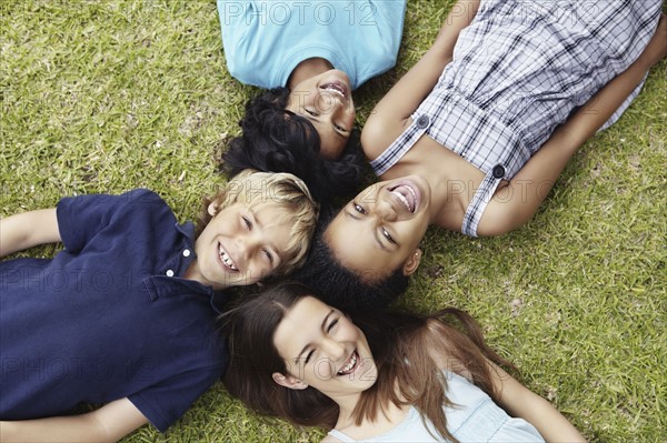 Four friends lying on the grass. Photo. momentimages