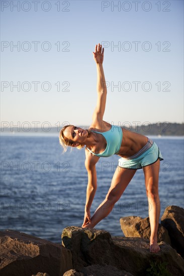 Athletic woman stretching by the ocean. Photo : Take A Pix Media