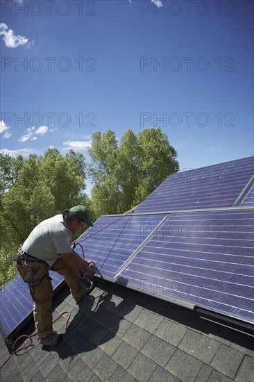 Construction worker installing solar panel on roof. Photo. Shawn O'Connor